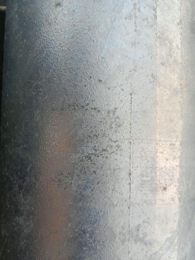 Galvanized tube with dark ash inclusions trapped in the coating