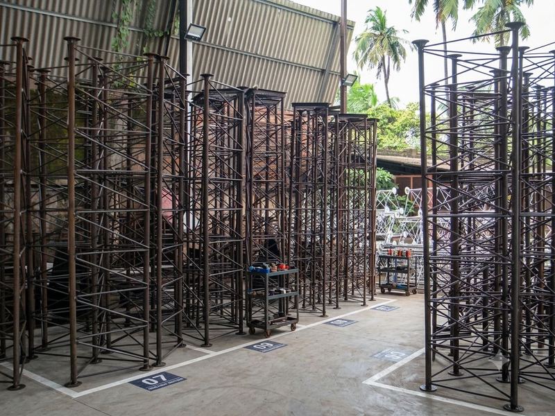 Fabricated sections in marked bays. Fabricated tower sections held in numbered floor-marked bays, awaiting galvanizing. Housekeeping is what makes a mark number findable six...