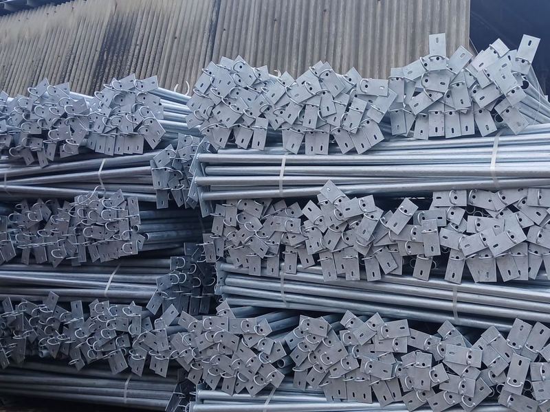 Galvanized poles and mounts. Galvanized tubular poles with fabricated brackets, bundled in the yard. Line hardware is small and cheap; the coating is what decides how long it...