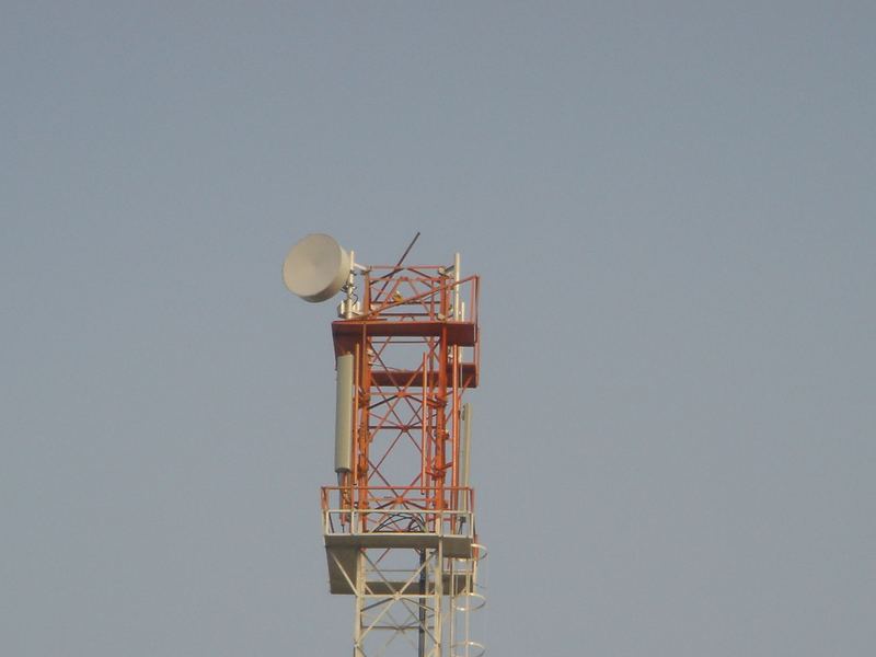 Telecom tower in service. A lattice telecom tower in service, in aviation marking, carrying a microwave dish and its platform. We have manufactured telecom towers since 1995.
